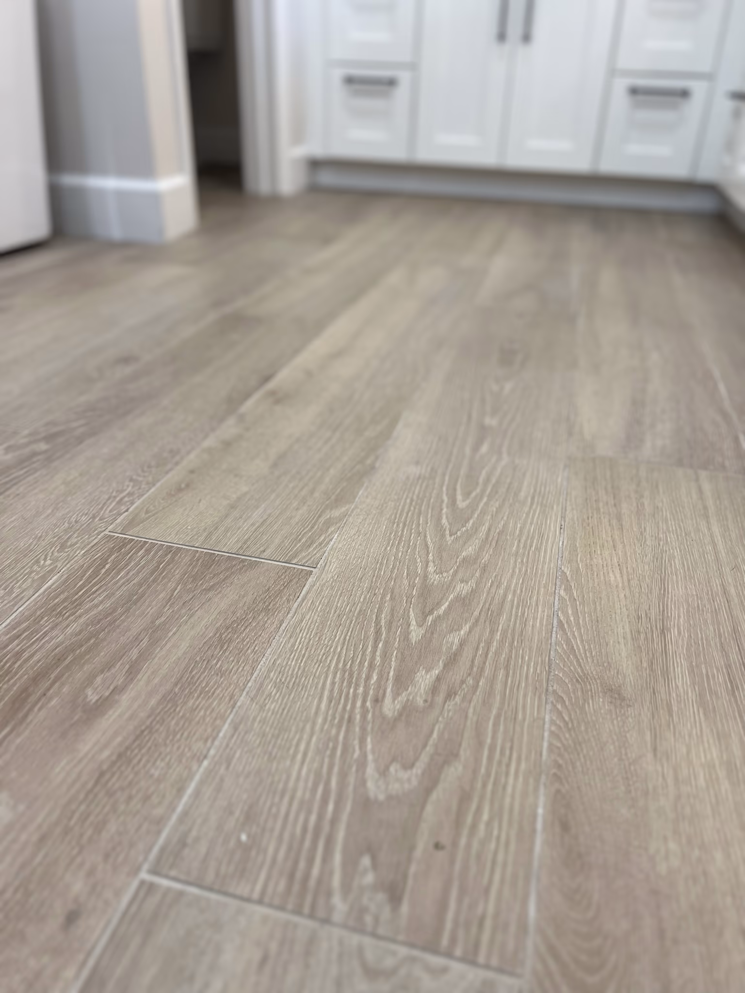 Close-up of the wood-look plank tile flooring, with the bathroom vanity in the background