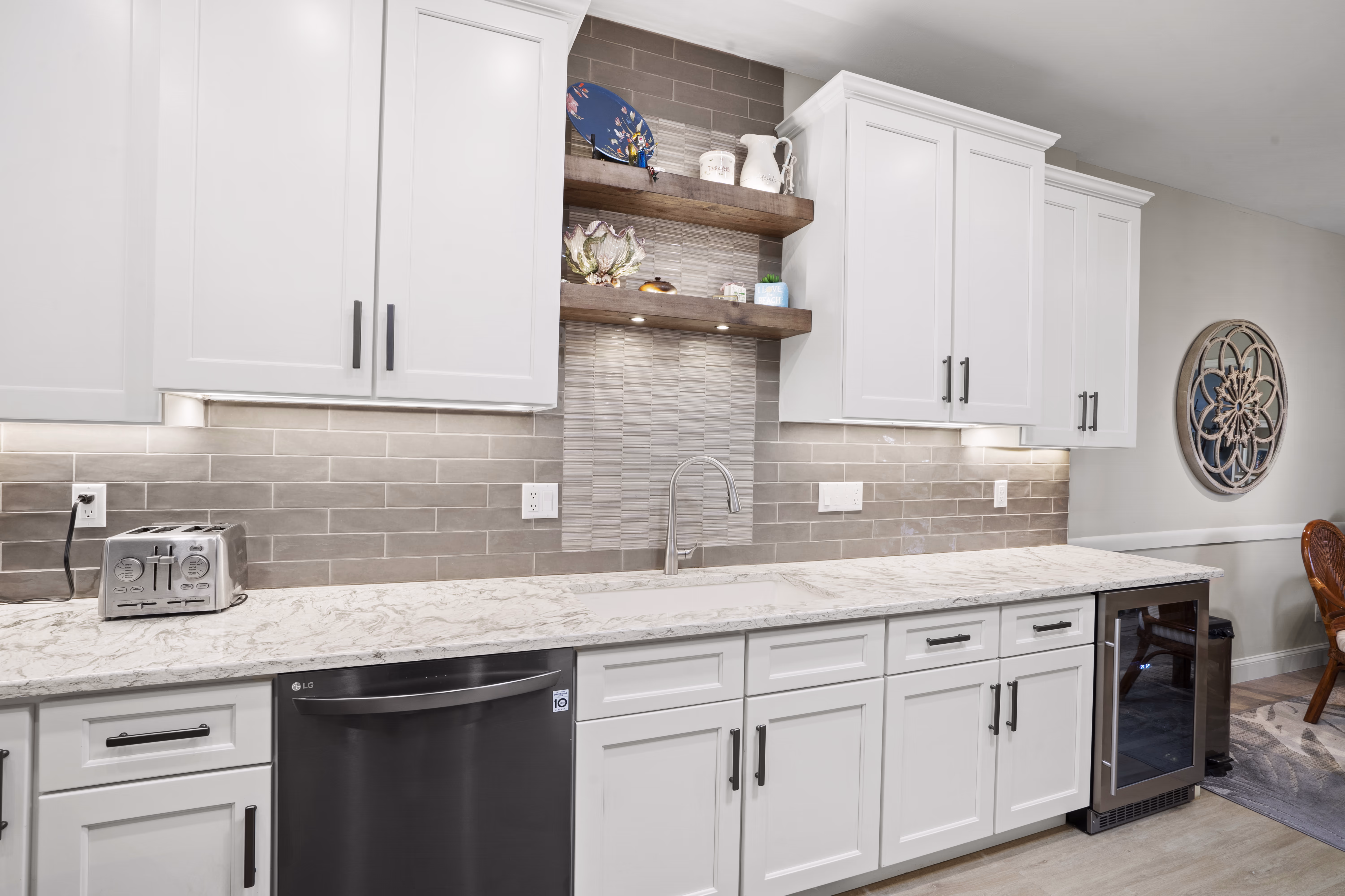 Kitchen sink area with a stainless faucet, mosaic tile accent, wood floating shelves, and a built-in wine cooler
