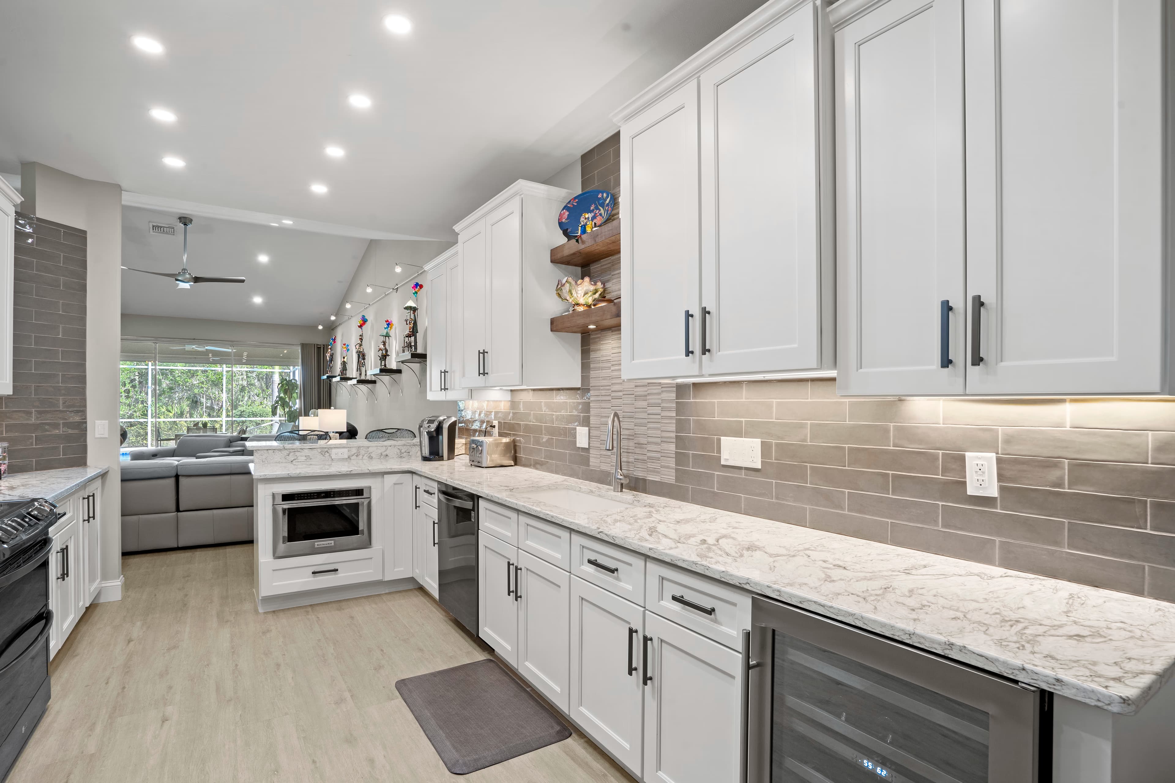 Kitchen with a built-in microwave drawer and quartz counters, opening to a living room with a grey sectional sofa