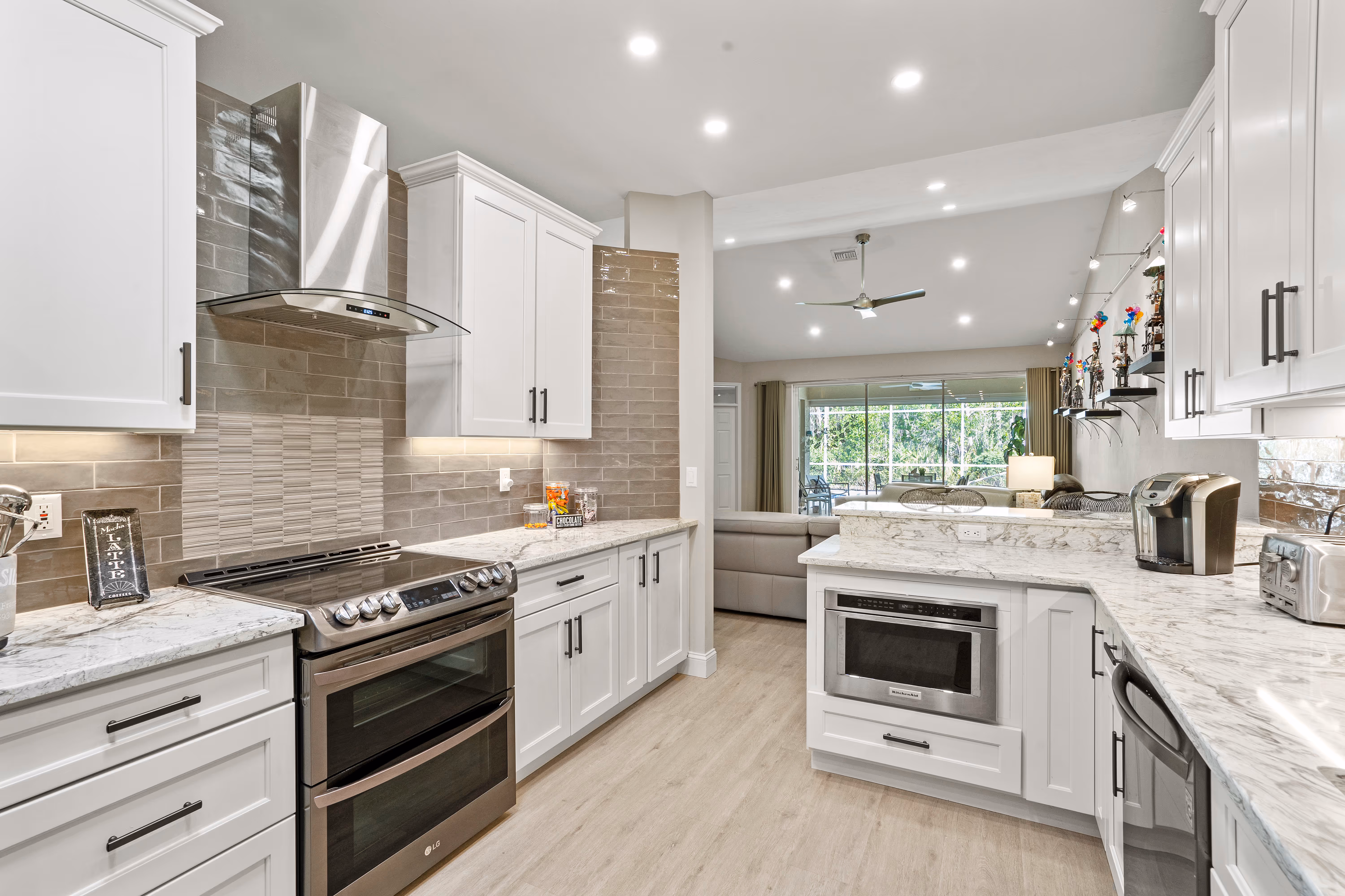 Stainless range hood over a black double-oven range, quartz counter, and mosaic tile backsplash
