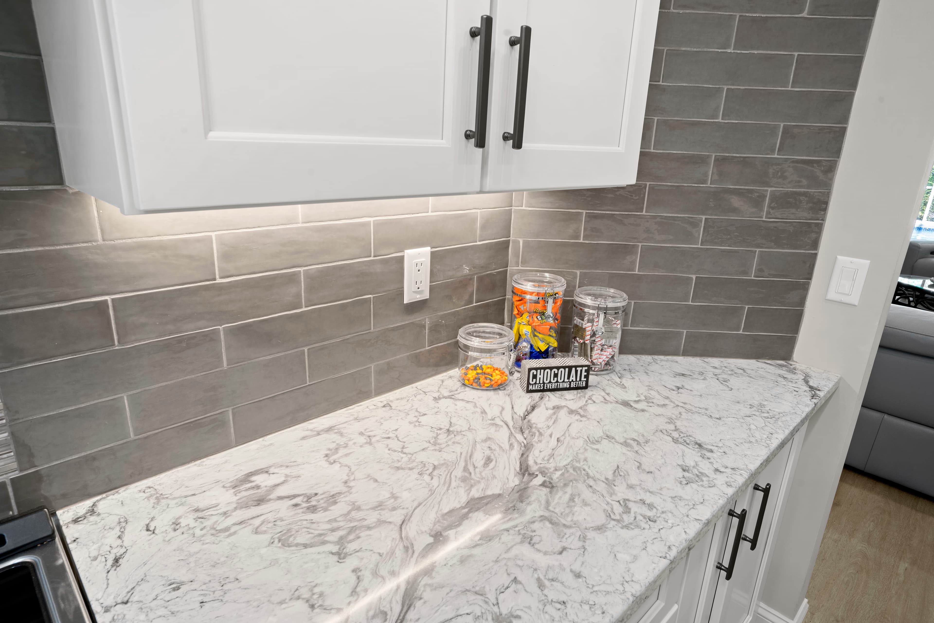 Close-up of white and grey marble-look quartz counter against a grey subway tile backsplash