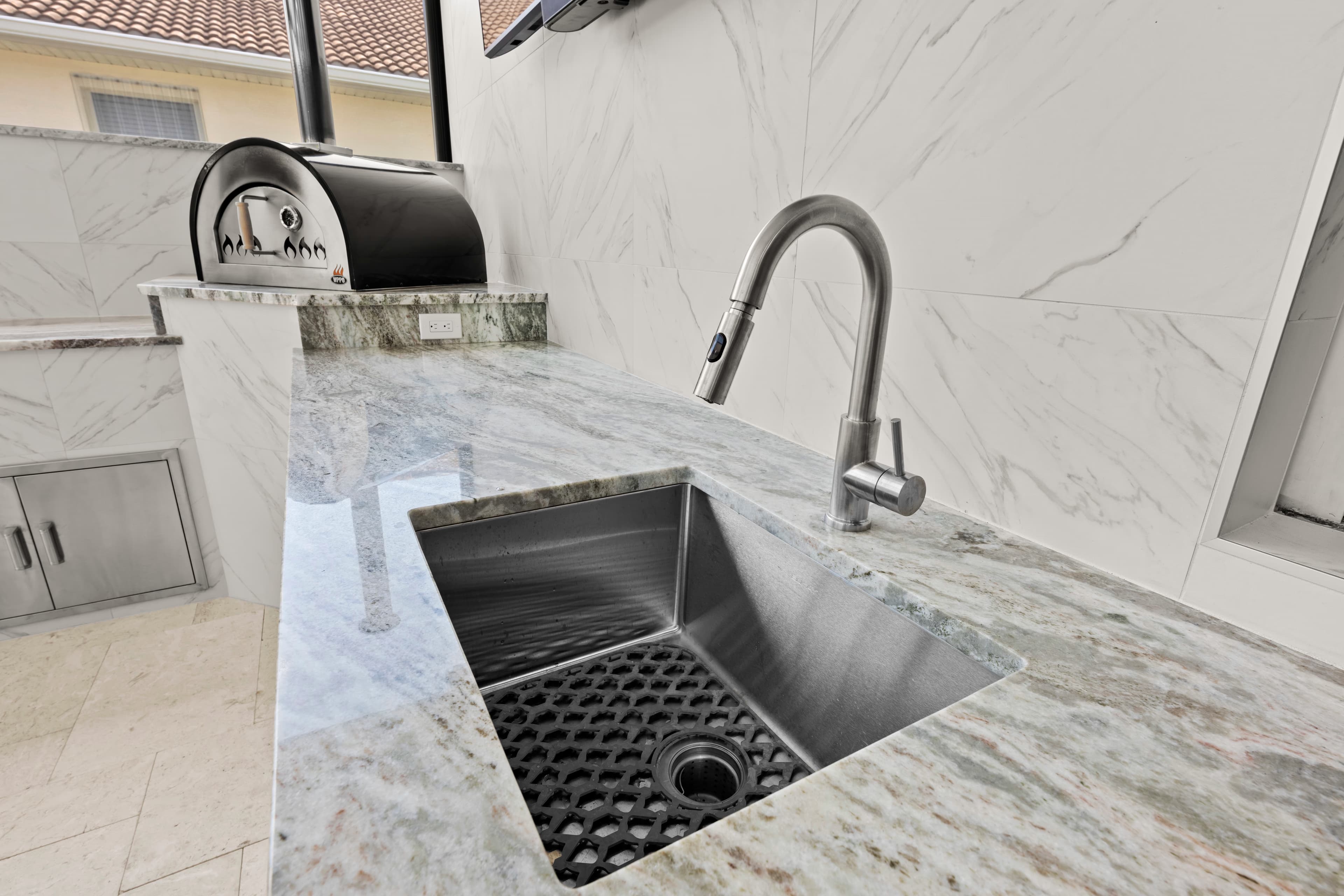 Close-up of an undermount stainless sink with a gooseneck faucet set into a granite counter