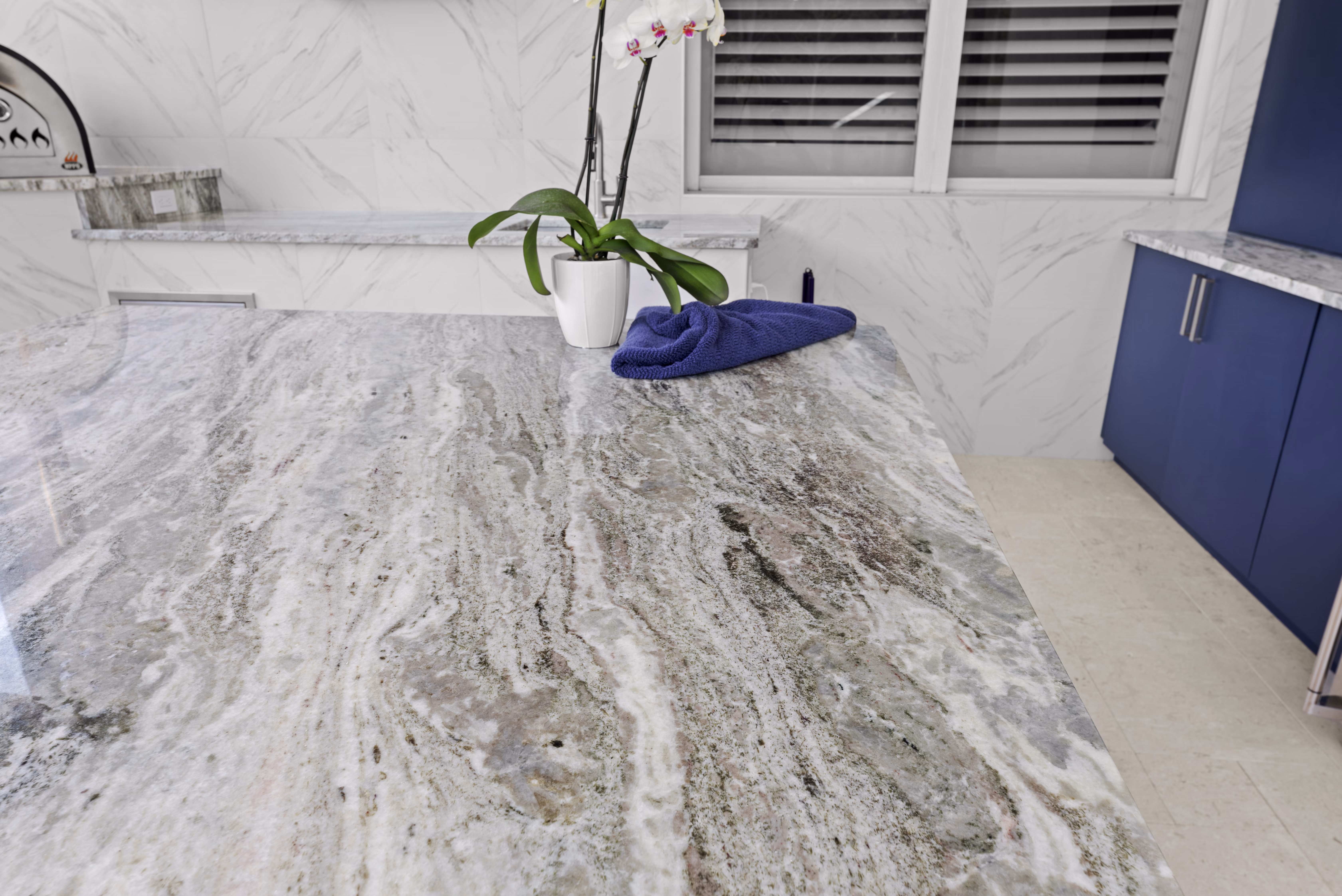 Close-up of the granite island surface with an orchid plant and a navy cloth