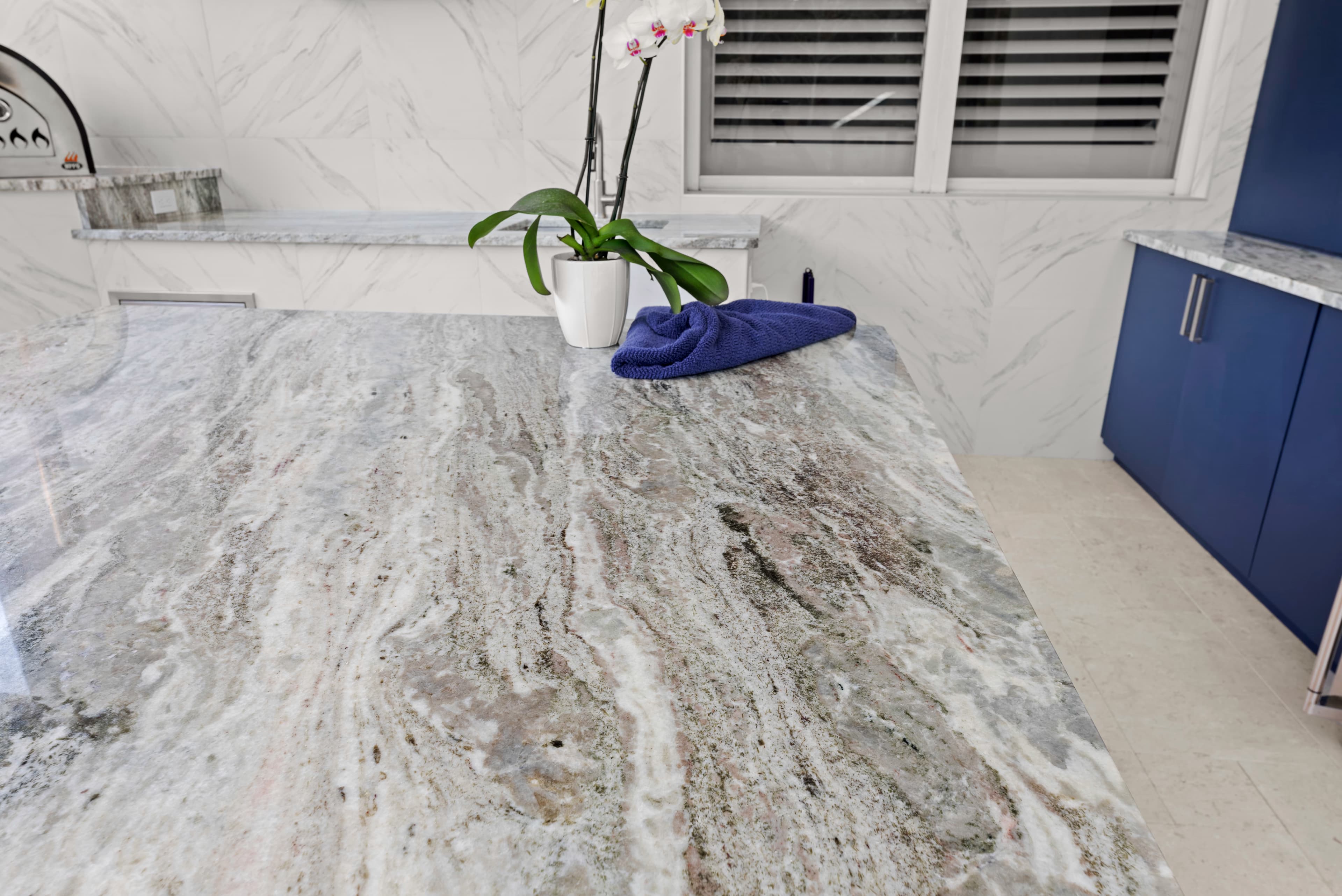 Close-up of the granite island surface with an orchid plant and a navy cloth